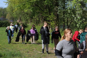 Zdjęcie przestawia uczestników Operacji Czysta Rzeka maszerujących wraz z workami na śmieci