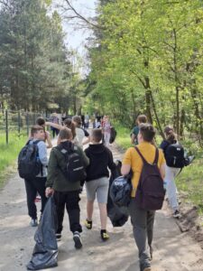 Zdjęcie przestawia uczestników Operacji Czysta Rzeka maszerujących wraz z workami na śmieci