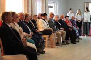 Zdjęcie przedstawia jubilatów siedzących na krzesłach