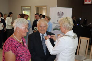 Zdjęcie przedstawia Burmistrza Miasta i Gminy Osjaków wręczającą medal za długoletnie pożycie małżeńskie Prezydenta Rzeczpospolitej Polskiej jubilatom