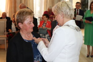 Zdjęcie przedstawia Burmistrza Miasta i Gminy Osjaków wręczającą medal za długoletnie pożycie małżeńskie Prezydenta Rzeczpospolitej Polskiej jubilatom